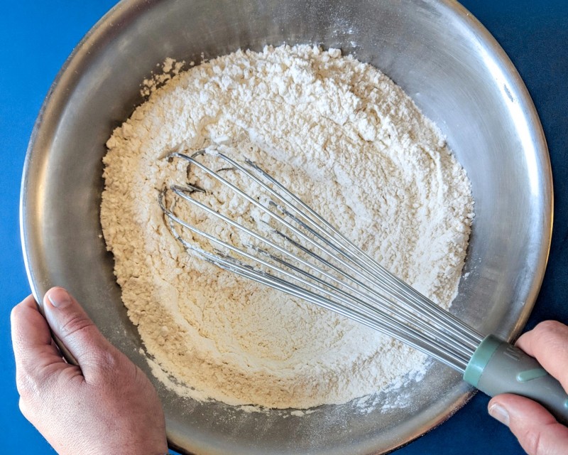 hands whisking blue background before measuring on kitchen scale